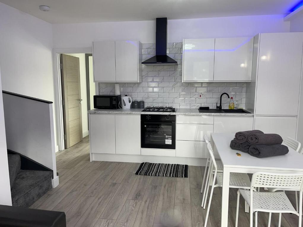 une cuisine avec des placards blancs et une table avec des chaises dans l'établissement Remarkable 3-Bed Apartment in London, à Hendon