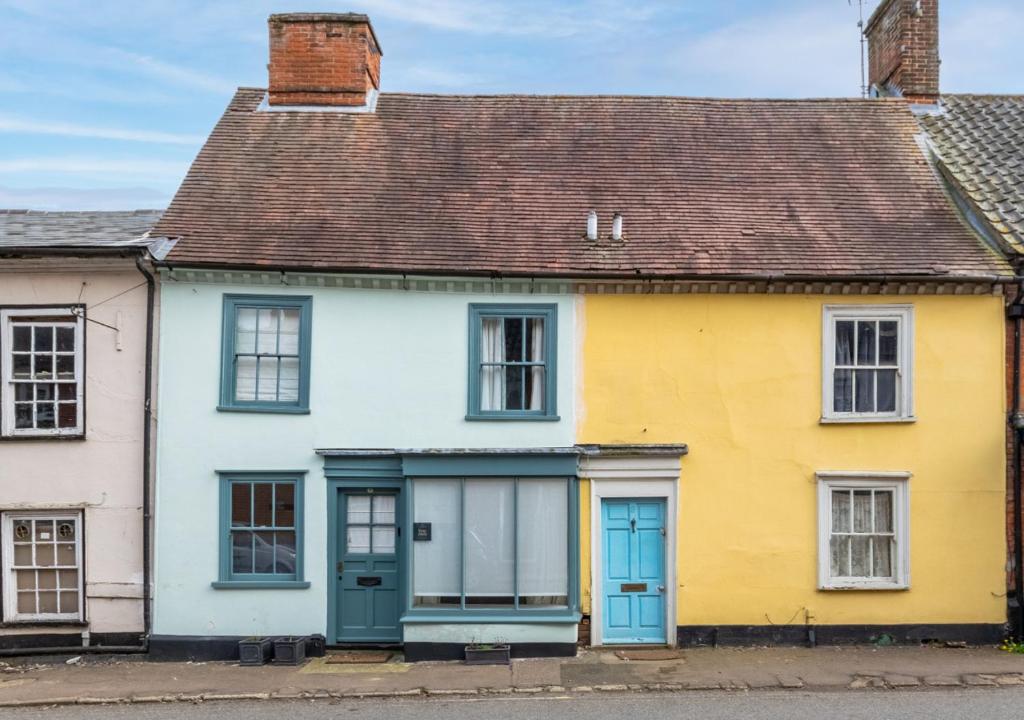 uma casa amarela e branca com portas azuis em London Cottage em Halesworth