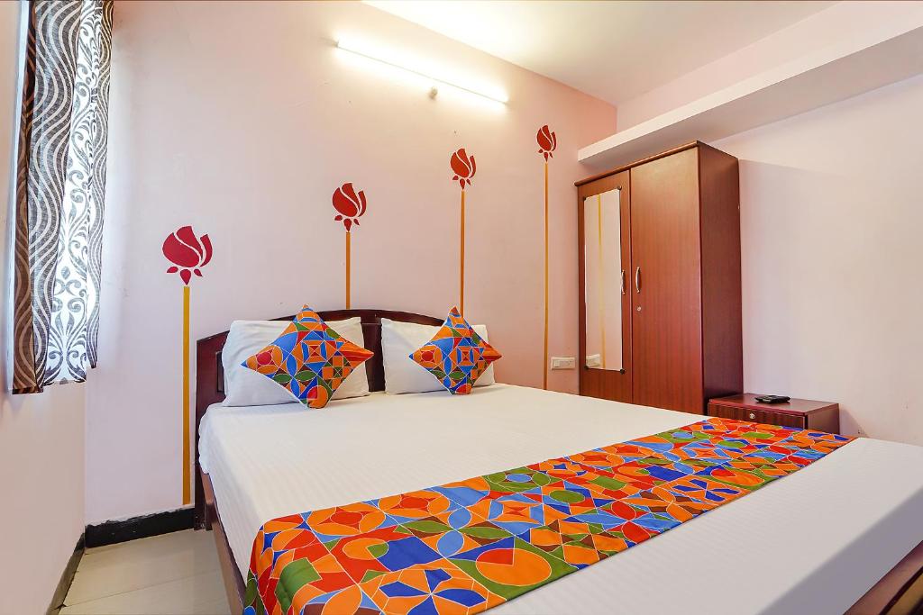 um quarto com uma cama grande e um cobertor colorido em FabExpress Sparrow Fern Palace em Ooty