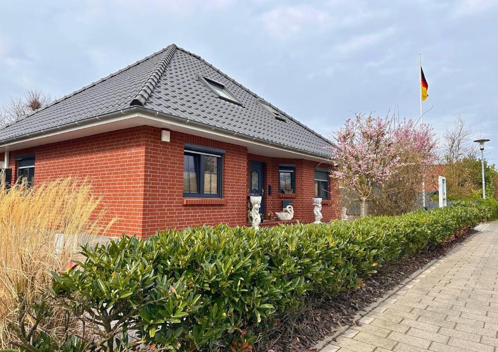 a red brick house with a black roof and bushes at Haus Seelotse in Otterndorf bei Cuxhaven in Otterndorf
