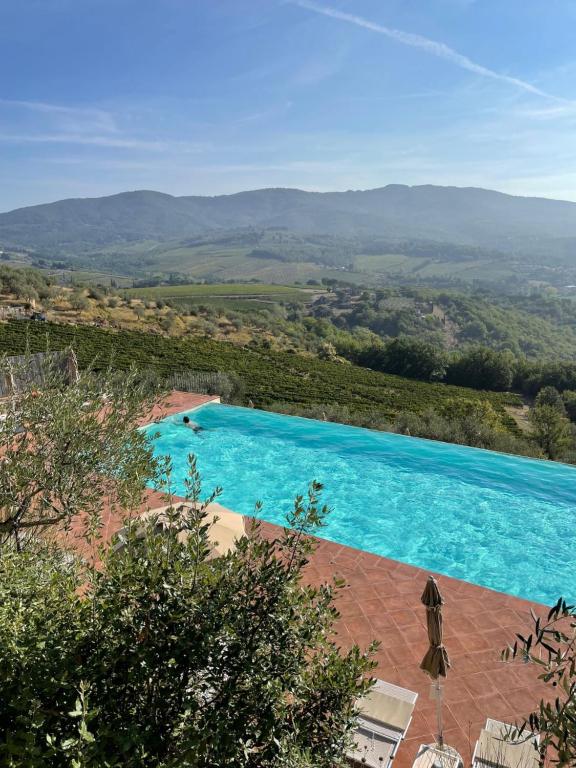 une grande piscine bleue avec des parasols dans l'établissement Castello Vicchiomaggio, à Greve in Chianti