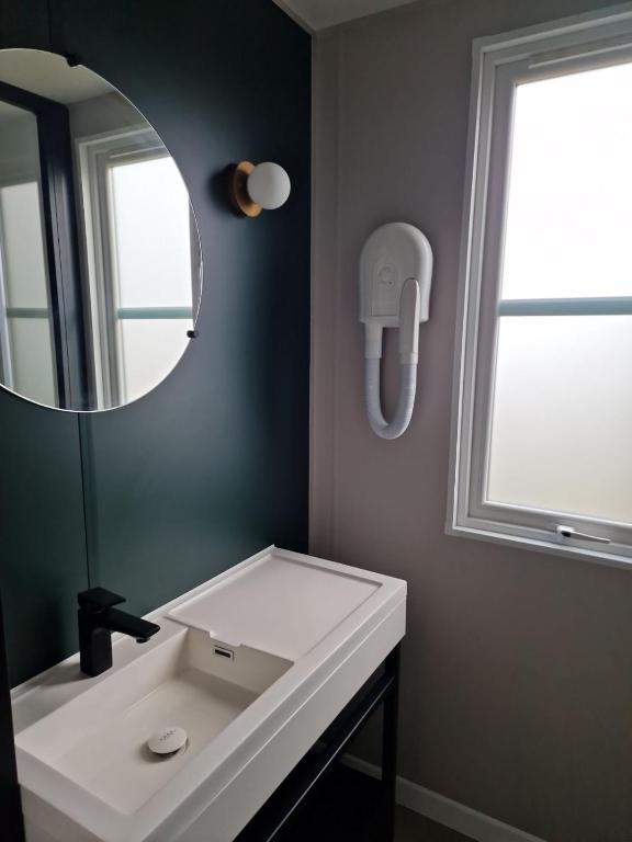 La salle de bains est pourvue d&#39;un lavabo blanc et d&#39;un miroir. dans l&#39;établissement PetraLegna, à Porto-Vecchio