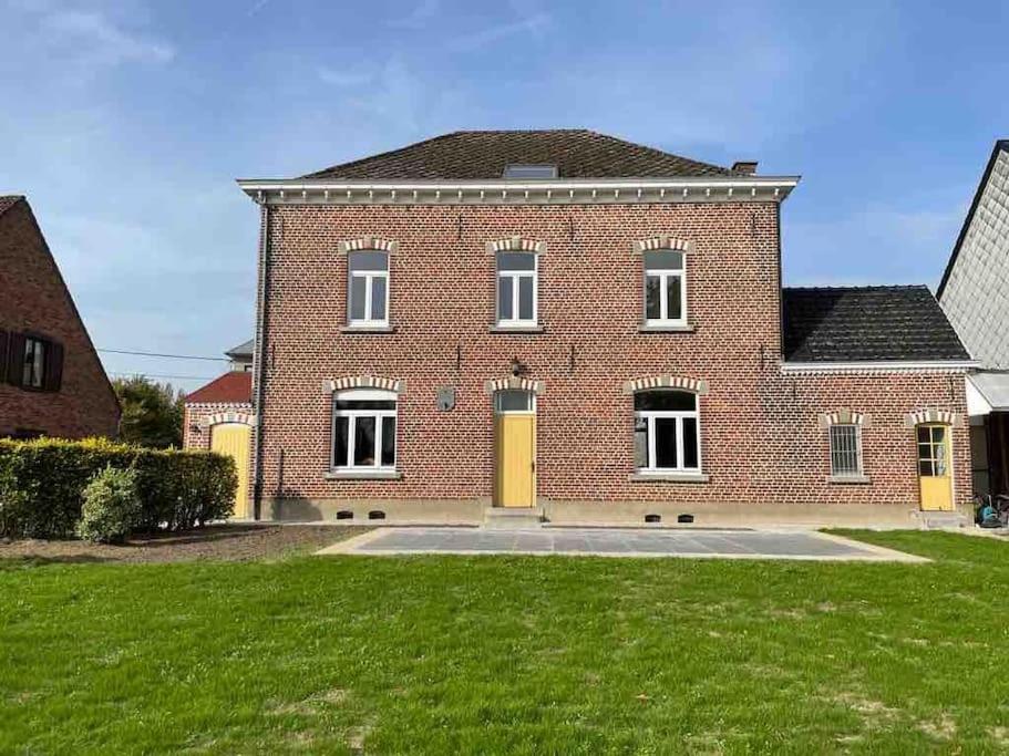 een groot bakstenen huis met gele deuren en een tuin bij Nieuw! Vakantiewoning Aventurien hartje Vlaamse Ardennen in Lierde