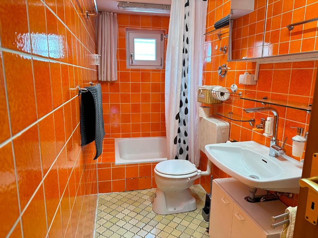 嘉格納的住宿－MELLoWY Monteure, TV, Küche, Bad，橙色浴室设有卫生间和水槽