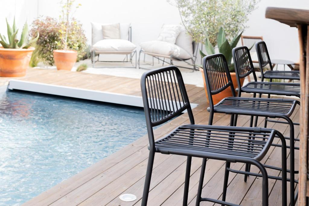 four chairs sitting on a deck next to a swimming pool at Casa Idalia Boutique Hotel in Comporta