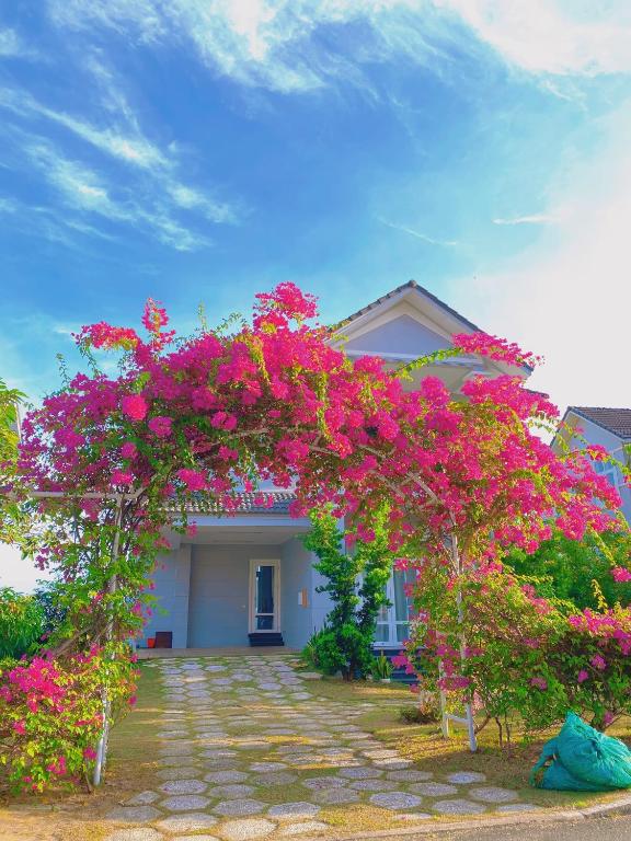 uma pérgola coberta de flores cor-de-rosa em frente a uma casa em SEALINKS VILLA em Ấp Phú Tịnh (2)