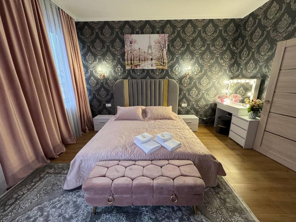 a bedroom with a bed with a pink bedspread and two bows at Emerald Apartament in Chernivtsi