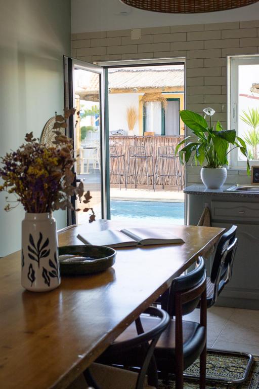 a wooden table with chairs and a vase with flowers at Casa Idalia Boutique Hotel in Comporta