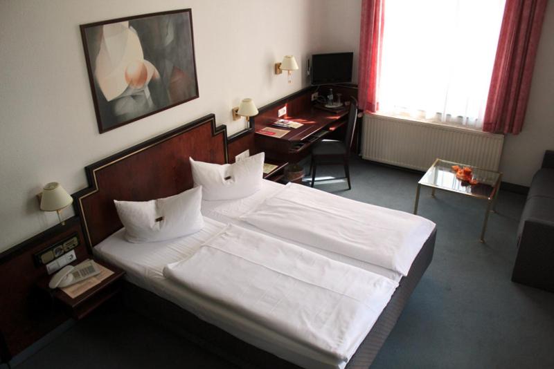 - une chambre avec un grand lit blanc et un bureau dans l'établissement Hotel Kipping, à Dresde