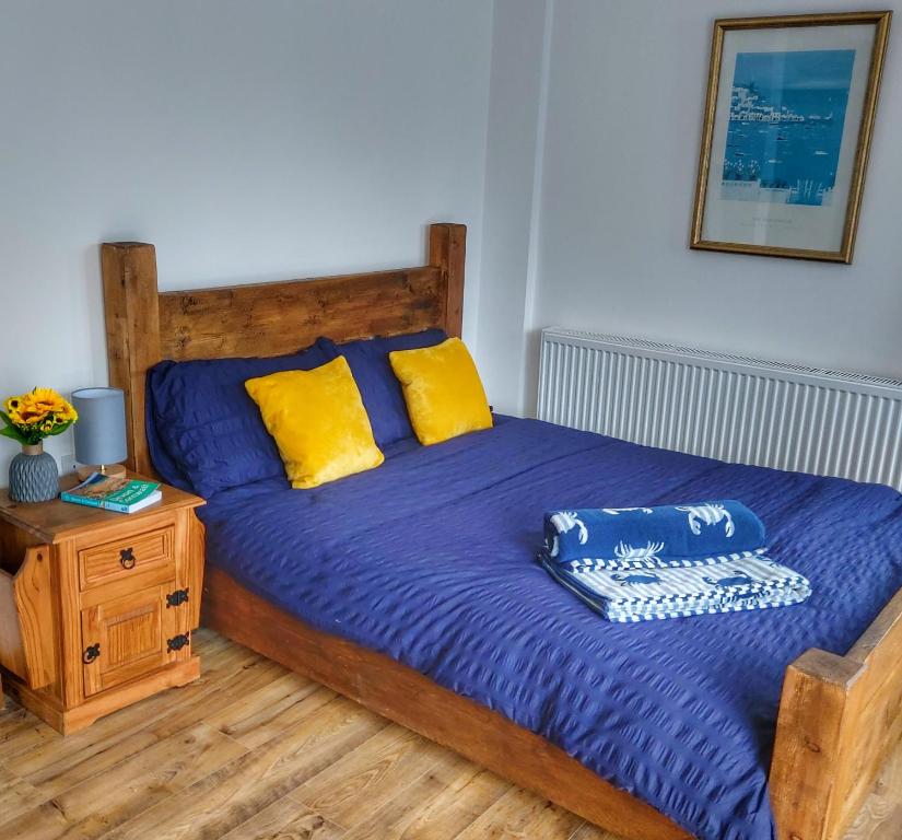 um quarto com uma cama com lençóis azuis e almofadas amarelas em Heart of Kernow Holidays em Bugle