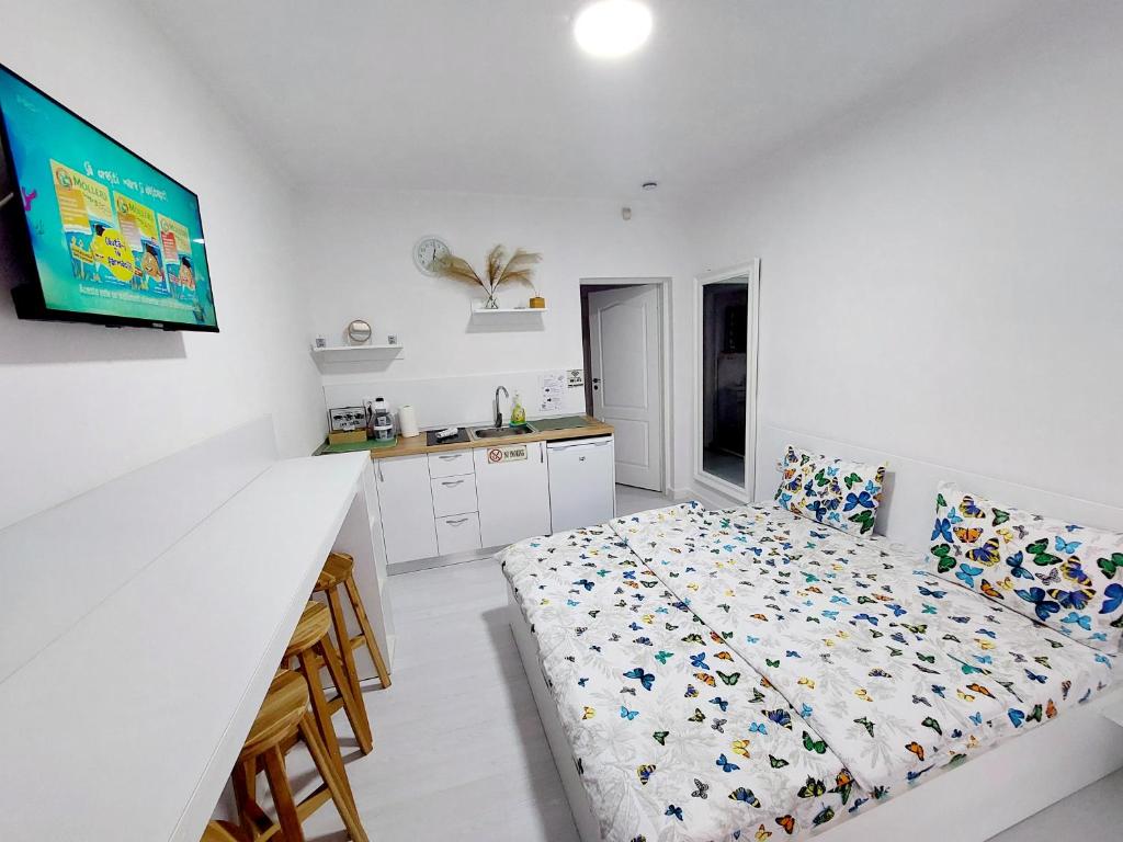 a white bedroom with a bed and a kitchen at Casuta cu Tei in Oradea