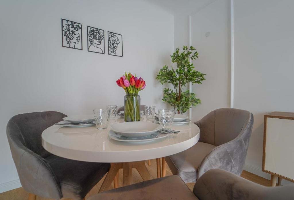 - une table à manger blanche avec des chaises et des fleurs dans l'établissement BelVie Residence, à Vienne
