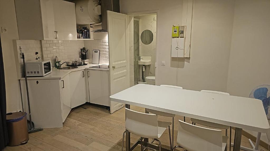 une cuisine blanche avec une table et des chaises dans l'établissement Appartement central 7 eme arrondissement, à Paris