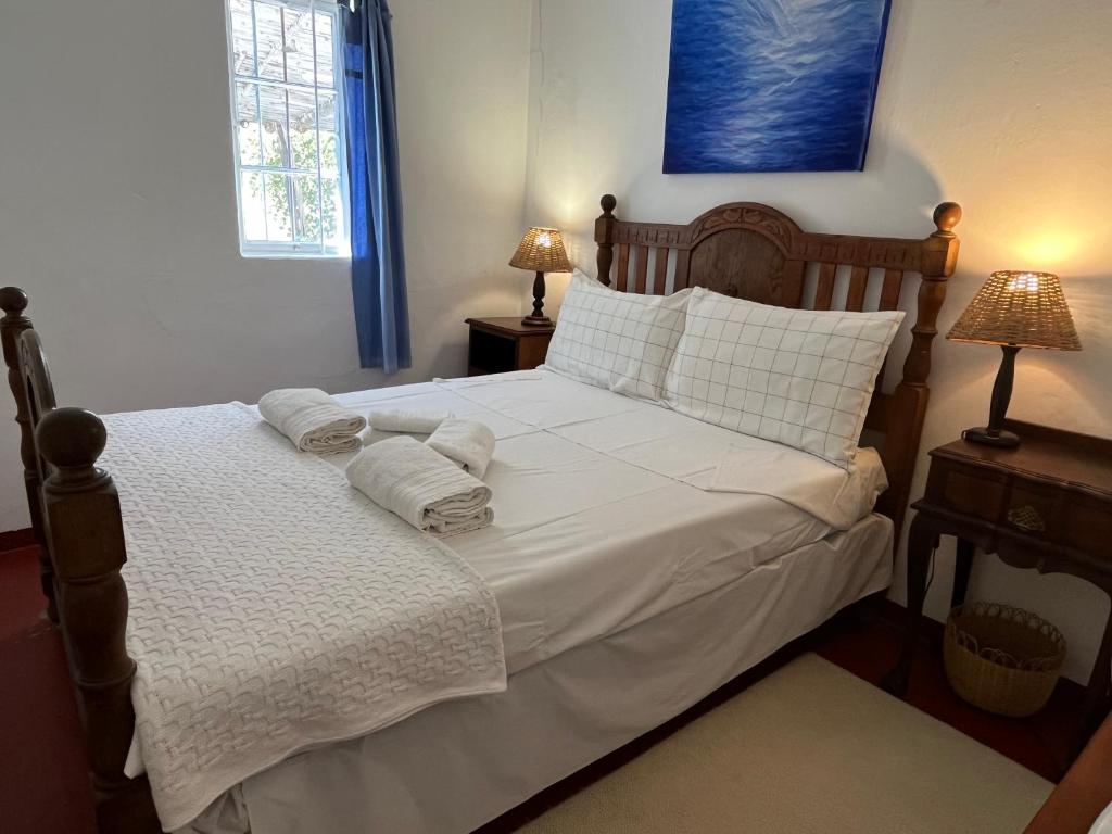 a bedroom with a bed with white sheets and pillows at Kom Kyk Cottage in Merweville in Merweville