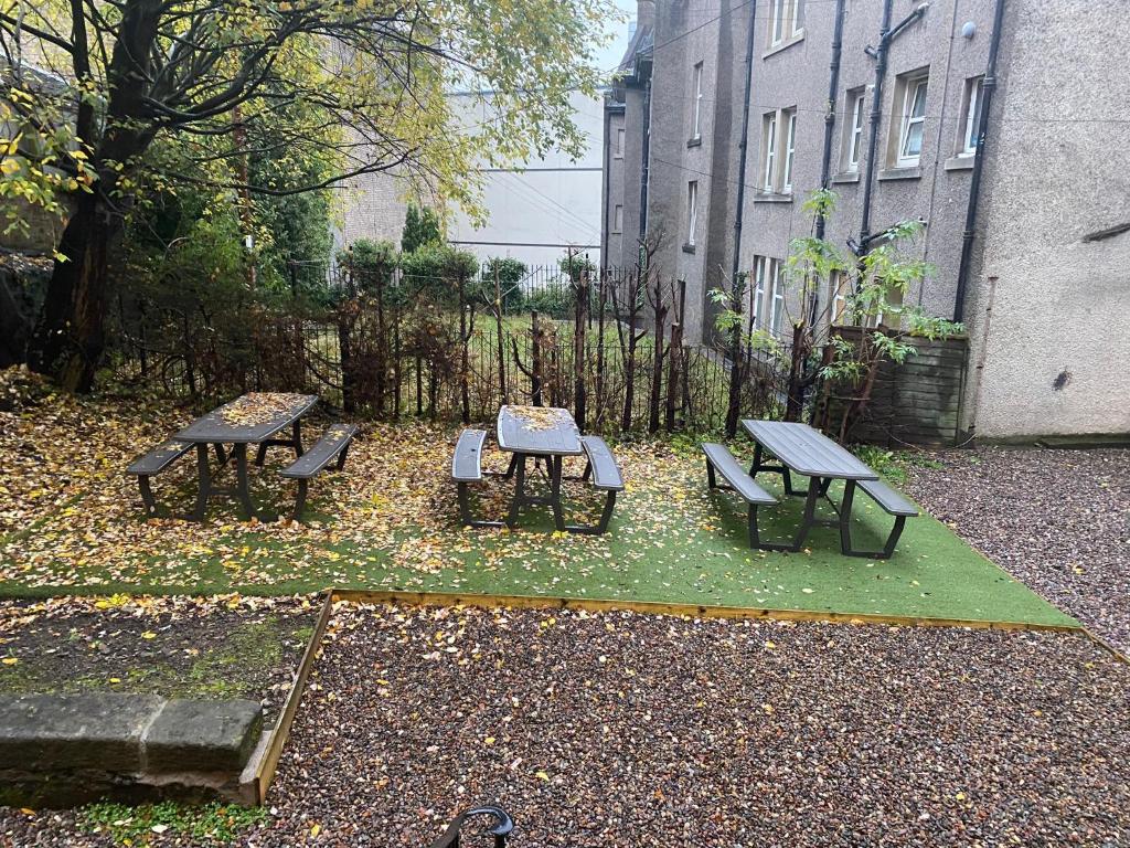 un grupo de mesas de picnic y bancos en un patio en Hamish Apartment en Stirling