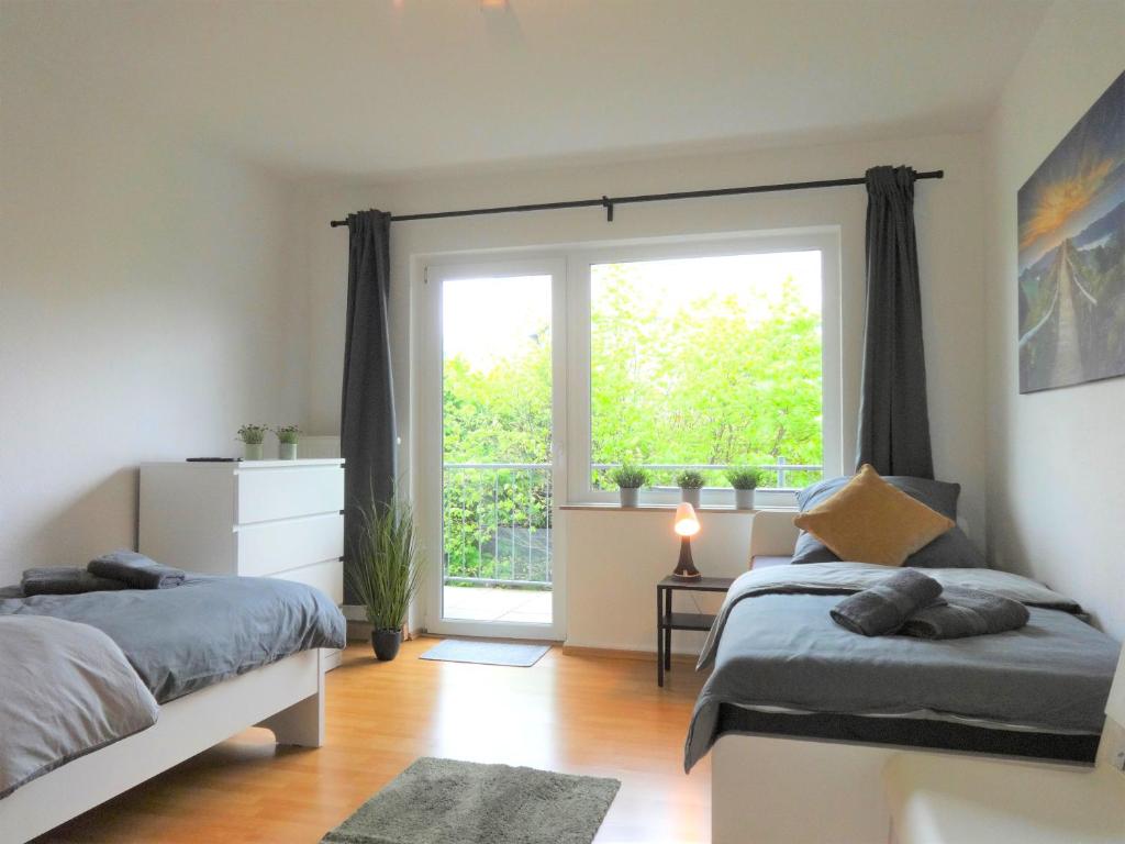 une chambre avec deux lits et une grande fenêtre dans l'établissement Helles Apartment mit Balkon für 5 Personen, à Schwerte