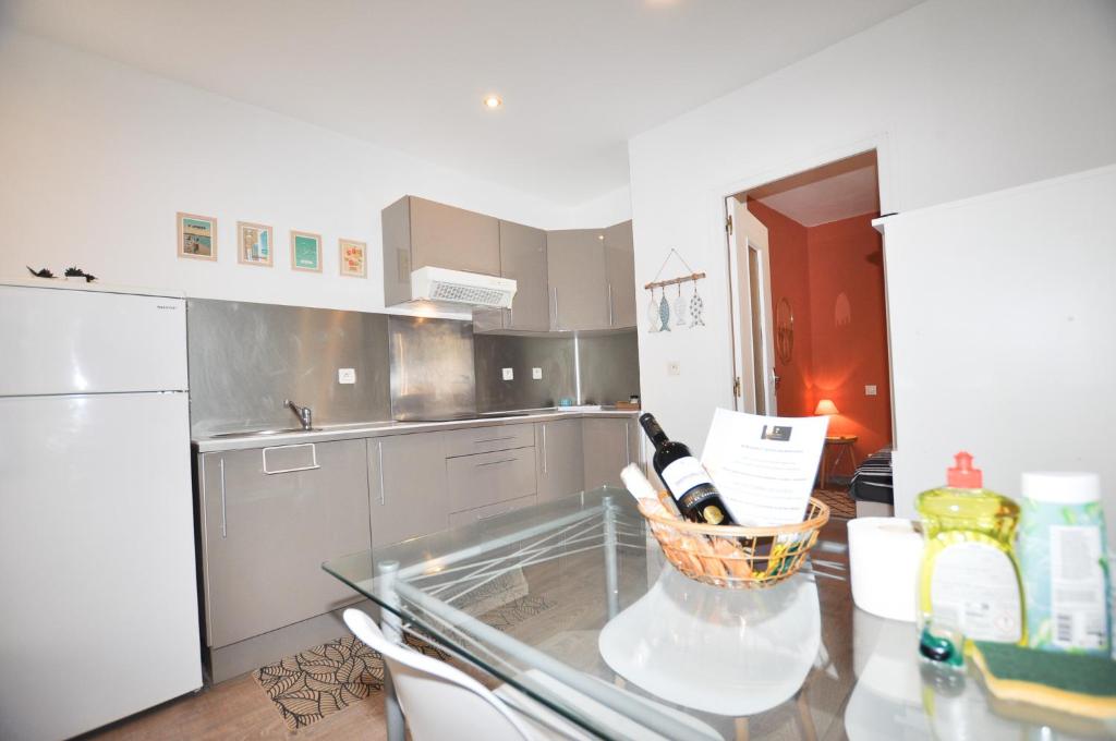uma cozinha com uma mesa de vidro com garrafas de vinho em Petite maison tout confort em Leucate