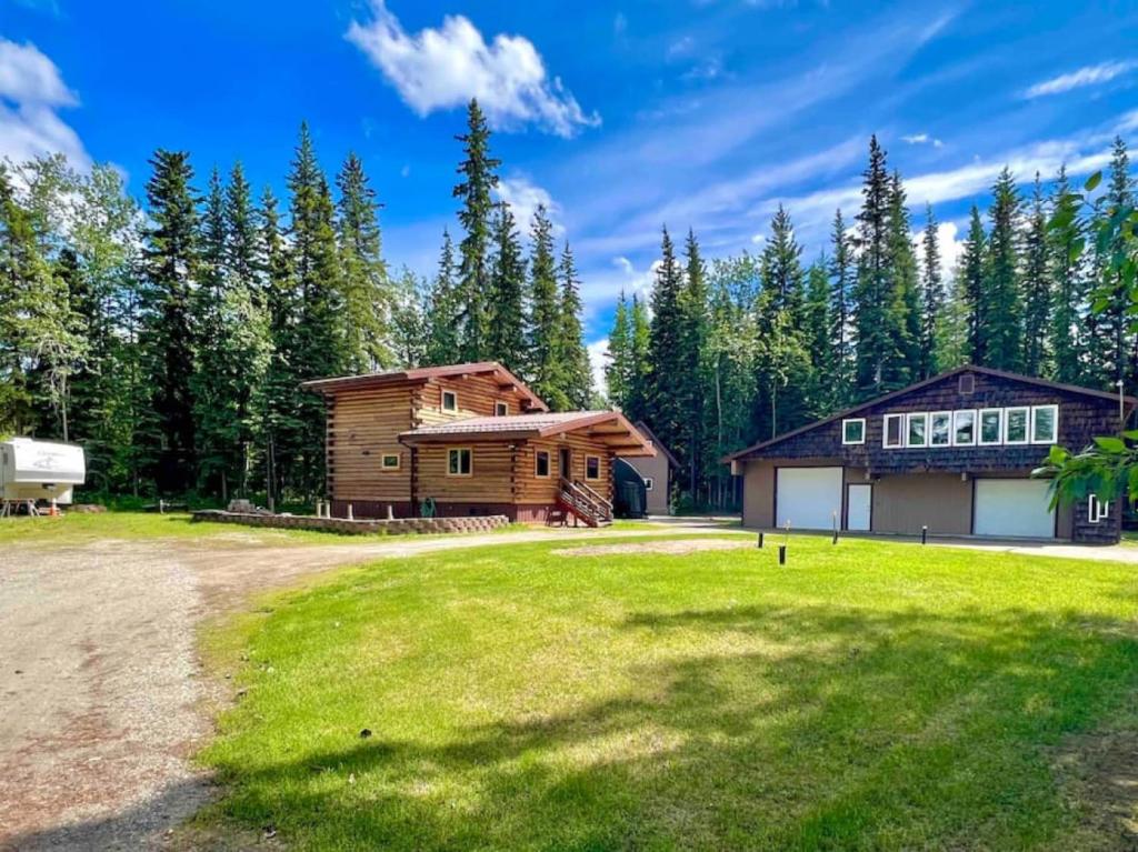 a log cabin with a grassy yard next to a house at Northern Dream Estates in Fairbanks