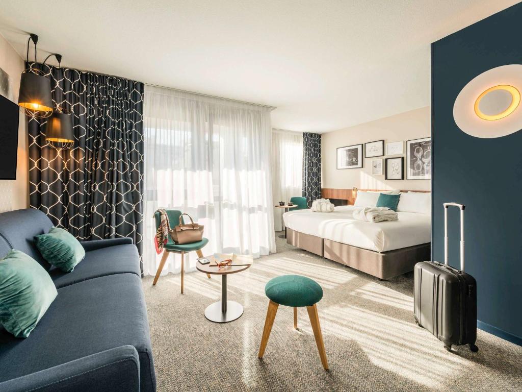 pokój hotelowy z łóżkiem i kanapą w obiekcie Mercure Paris Montparnasse Pasteur w Paryżu