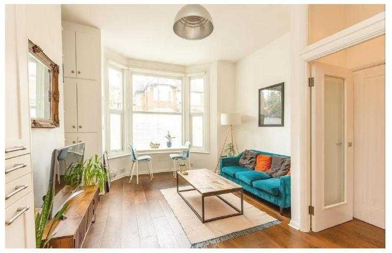 Stylish, 2 Bed Apartment, Muswell Hill في لندن: غرفة معيشة مع أريكة زرقاء وطاولة