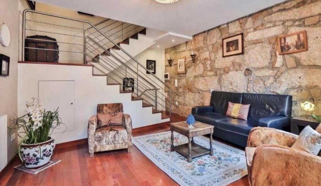 ein Wohnzimmer mit einem Sofa und einer Steinmauer in der Unterkunft Amazing Flat Sao Bento in Porto