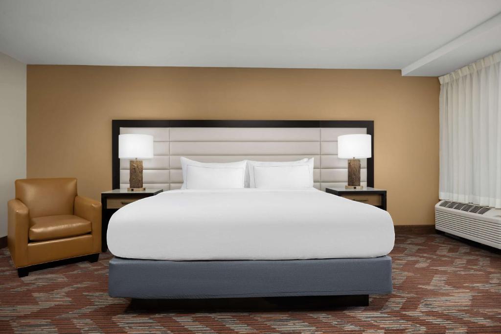 ein Schlafzimmer mit einem großen weißen Bett und einem Stuhl in der Unterkunft Doubletree By Hilton Greensboro Airport in Greensboro