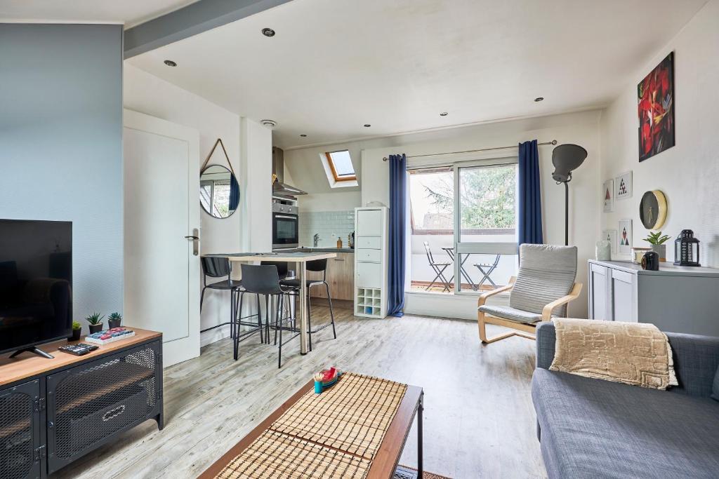 un salon avec un canapé, une table et une cuisine dans l'établissement Au Jardin de Mel - Appt à moins d'1 km de la plage, à Courseulles-sur-Mer