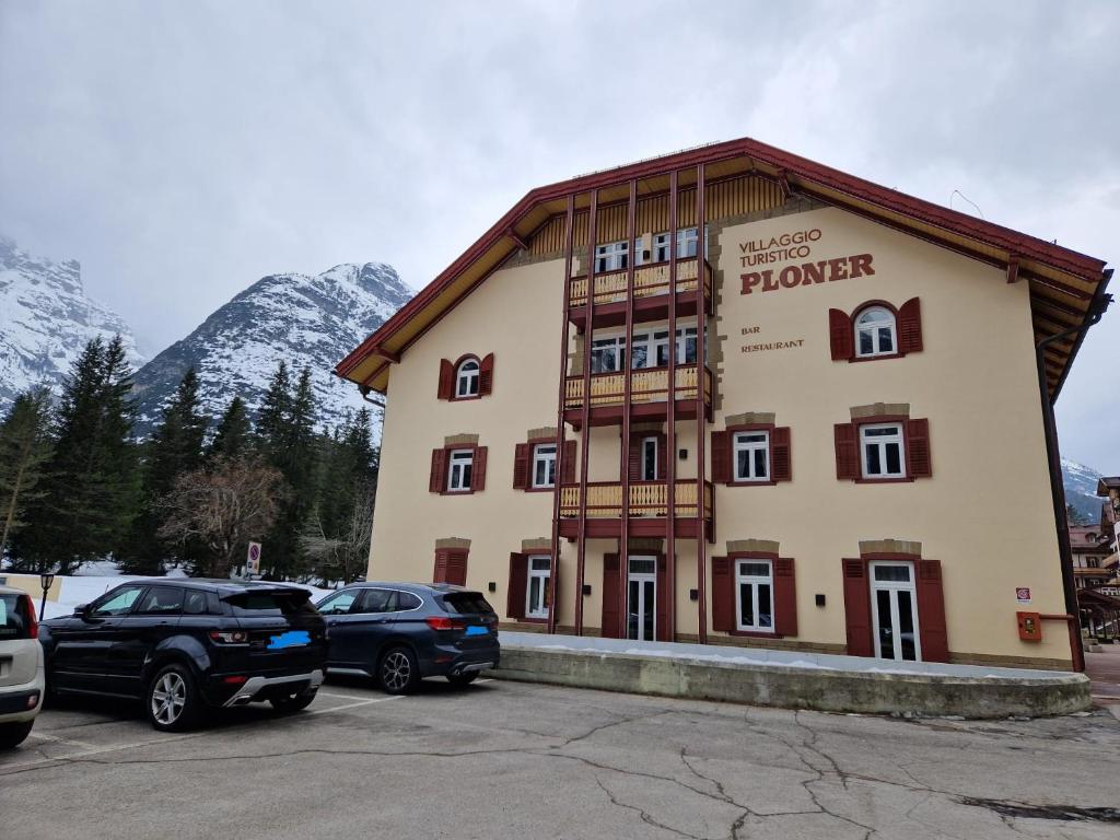 un gran edificio con coches estacionados en un estacionamiento en Villaggio Turistico Ploner - nel cuore delle Dolomiti tra Cortina e Dobbiaco, en Dobbiaco