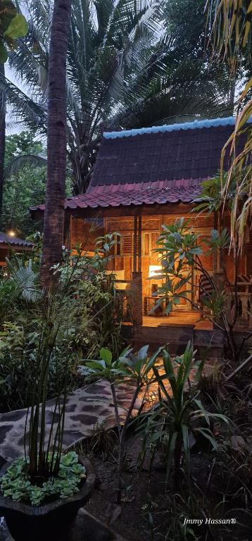 uma casa de madeira com um telhado roxo num jardim em Villas Light House - Eco-Traditional Joglo em Gili Trawangan