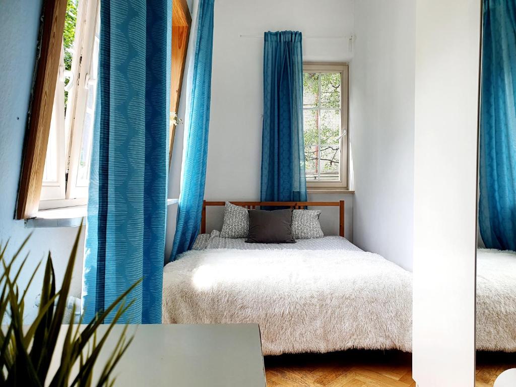 a small bedroom with blue curtains and a bed at Tanie pokoje w centrum in Sopot