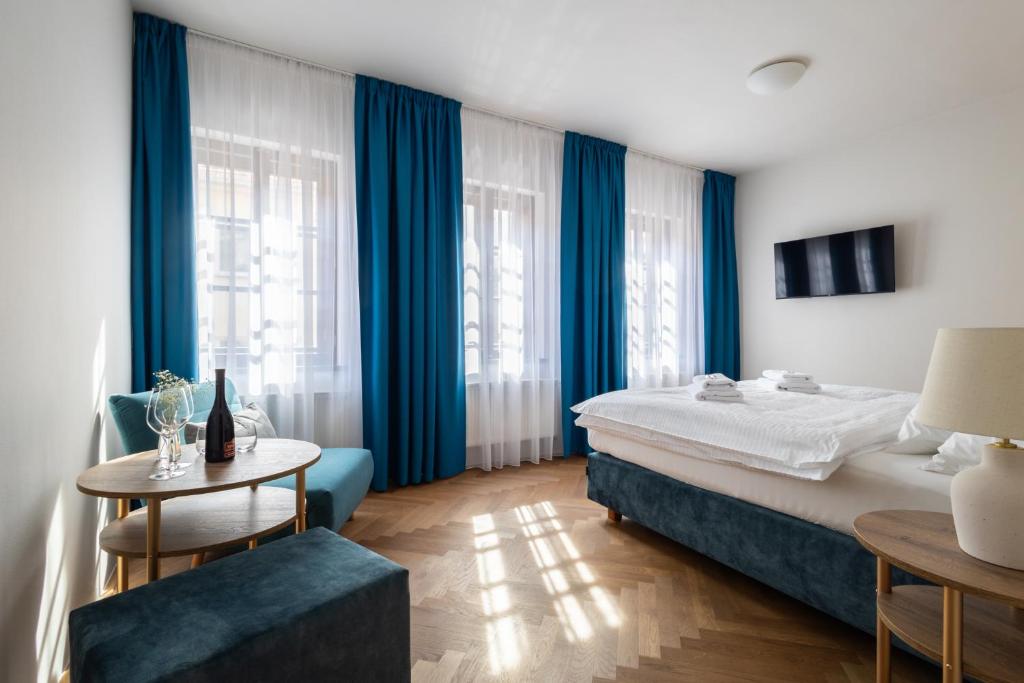 Hotel Tanzberg Mikulov في ميكولوف: غرفة نوم مع ستائر زرقاء وسرير وطاولة