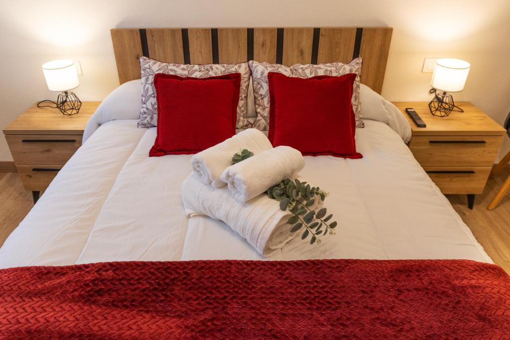 1 cama blanca grande con almohadas rojas y toallas. en Apartamento Larrazu Agroturismo Baztán, en Arráyoz