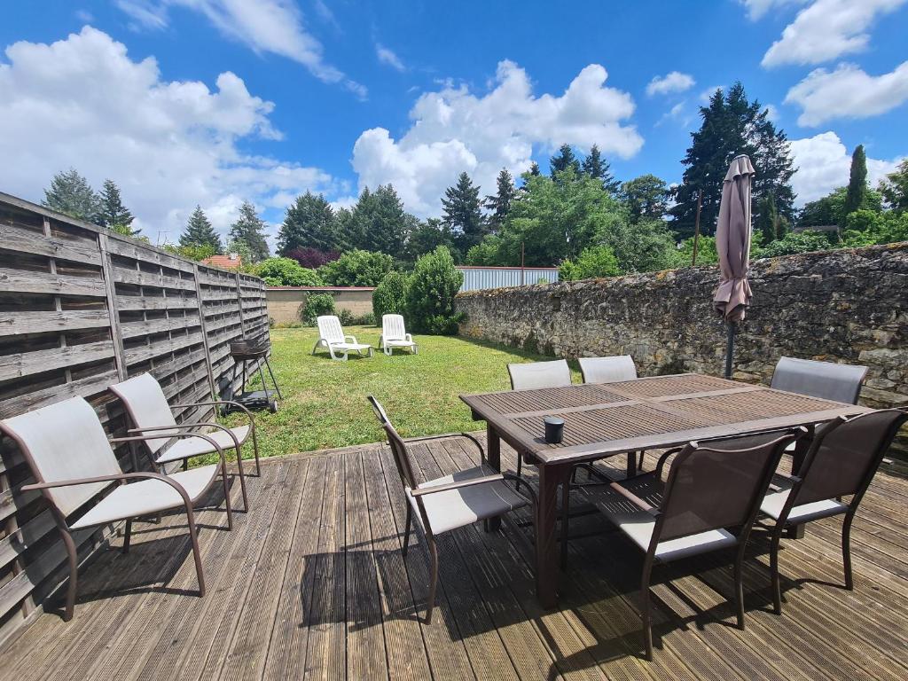 a wooden table with chairs and an umbrella on a deck at Charmante maison avec jardin, au cœur du Berry, proche rivière et randonnées - FR-1-591-57 in Chasseneuil