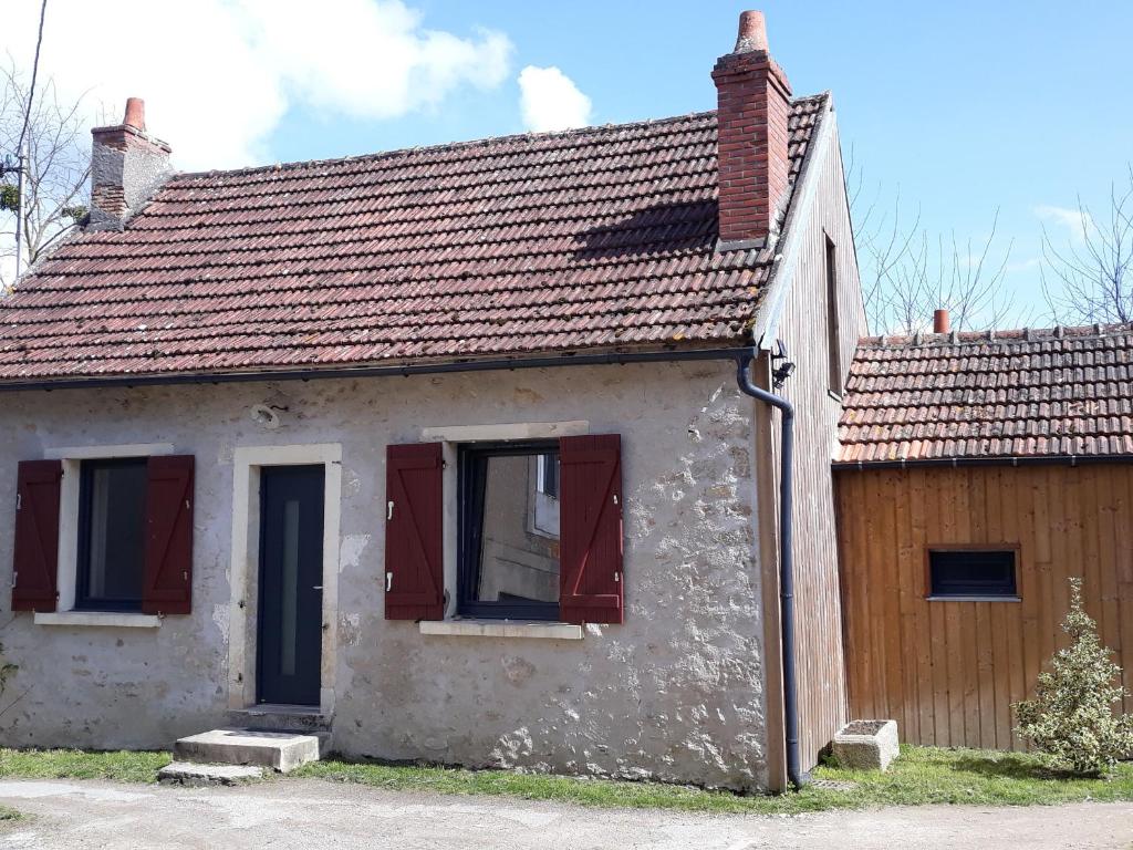 a small house with red windows and a wooden door at Maison avec jardin, piscine chauffée et baignade à proximité - Le Menoux - FR-1-591-234 in Le Menoux