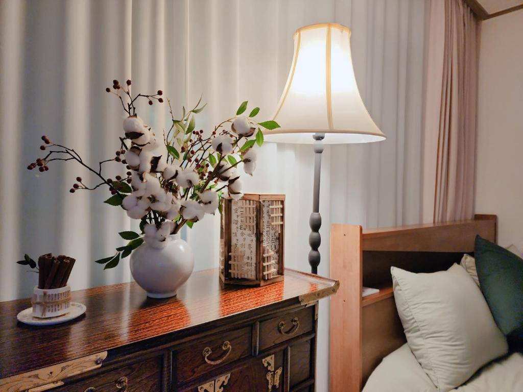 a table with a vase of flowers and a lamp at JB Stay#Hongdae & Sinchon 10min#Double Room in Seoul