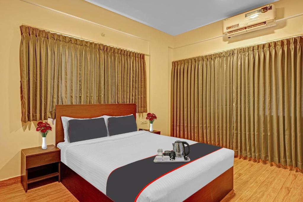 a hotel room with a bed with a phone on it at Super OYO Manyata Stay-In in Bangalore