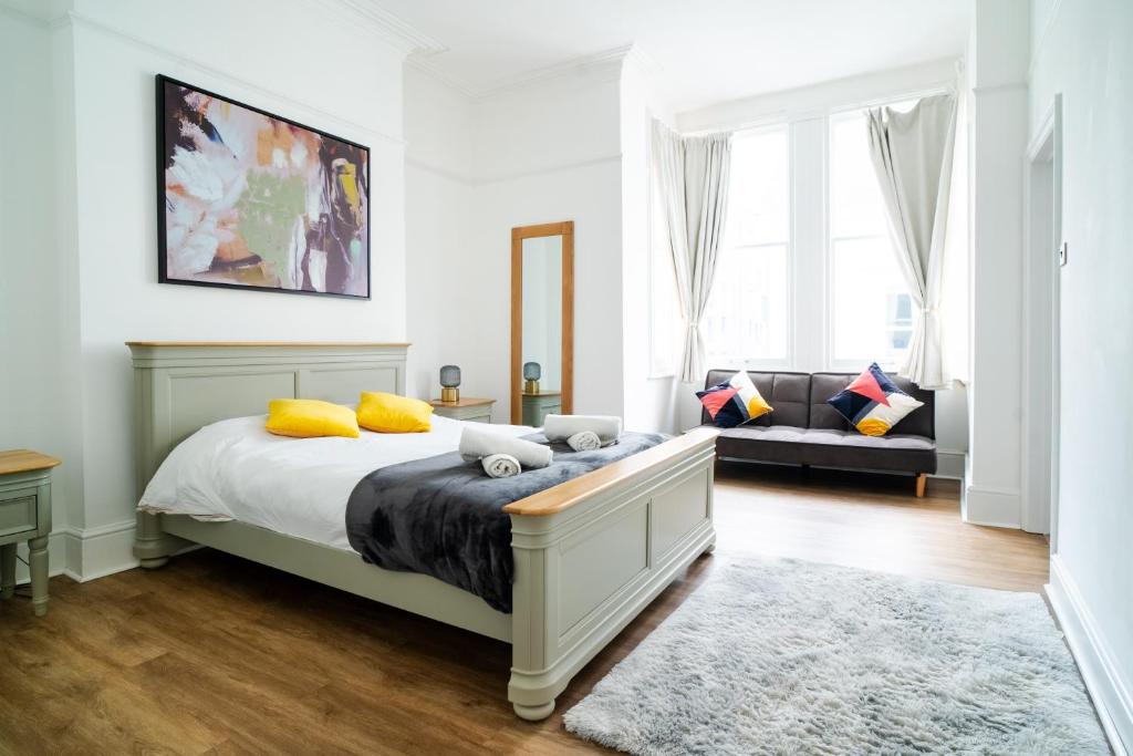 1 dormitorio con cama con almohadas amarillas y sofá en Plymouth Hoe - Beautiful 5 Bedroom Victorian House - Central Location en Plymouth