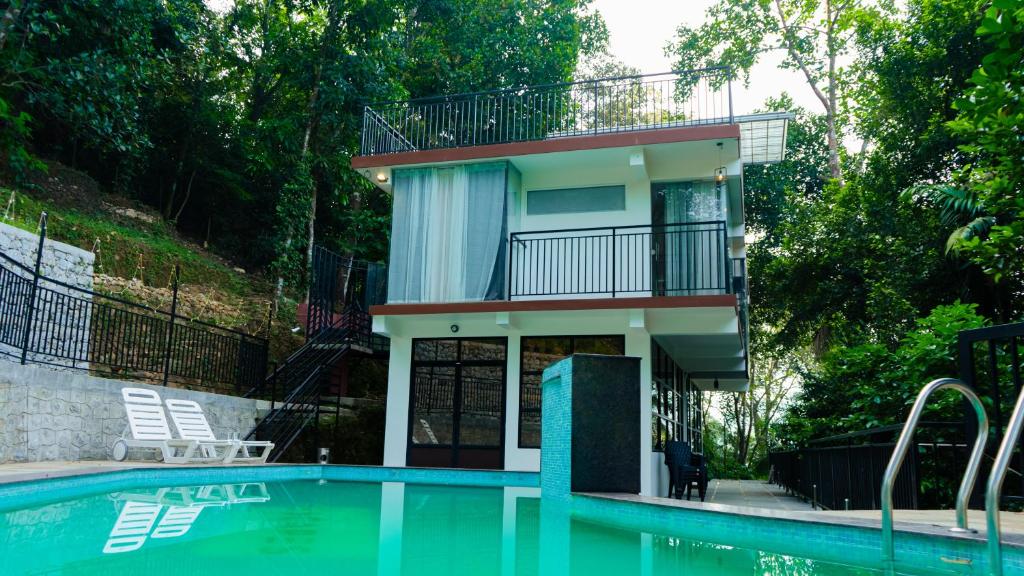 a house with a balcony next to a swimming pool at Escape Resorts Vayalada in Kozhikode