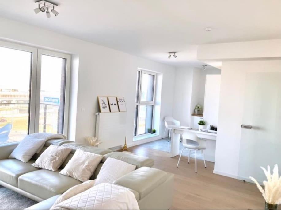 een witte woonkamer met een bank en een bureau bij Luxury apartment with stunning view - Guillemins in Brussel