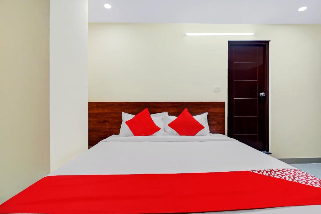 - une chambre avec un lit blanc et des oreillers rouges dans l'établissement Super OYO Hotel Silver House Near Mantri Square Mall, à Bangalore