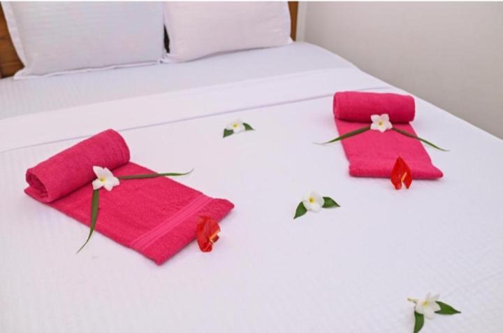 a bed with two pink towels and flowers on it at Negombo Royal Villa by Oviniru in Negombo