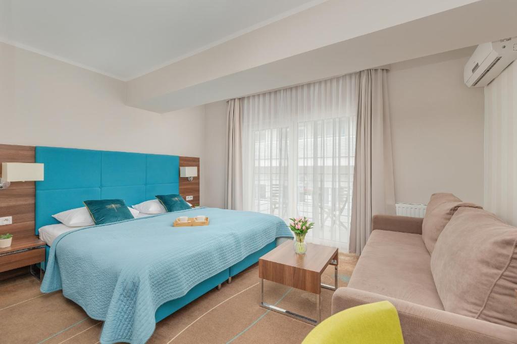 a bedroom with a blue bed and a couch at Promenada Gwiazd Międzyzdroje Studio z Balkonem i Klimatyzacją by Renters in Międzyzdroje