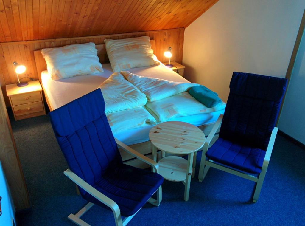 a bedroom with a bed and two chairs and a table at Hostinec U Pejska a Kocicky in Mariánské Lázně