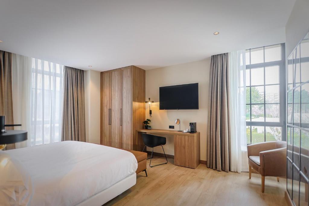 een hotelkamer met een bed, een bureau en een televisie bij Hotel & Spa Convento San Francisco in Soria