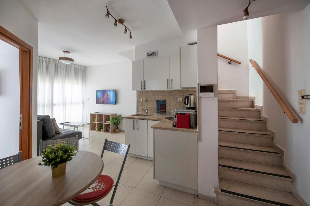 a kitchen and living room with a staircase and a table at 2BD and 2 Bath duplex on the Hilton beach with a shelter in Tel Aviv