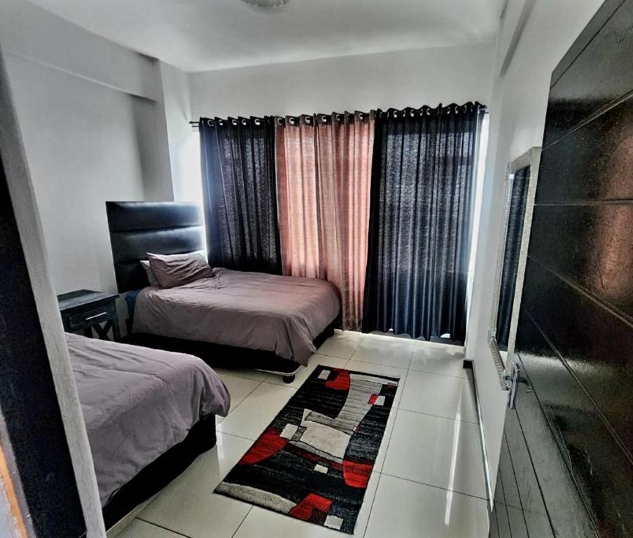 a small room with two beds and a window at Beachurst Apartment in Durban