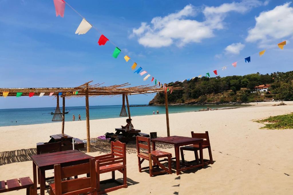 a group of tables on a beach with flags at Klong Jark Bungalows in Ko Lanta