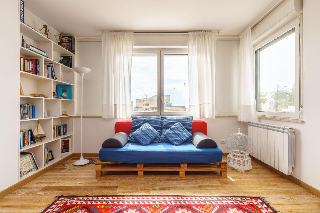sala de estar con sofá azul frente a una ventana en Italianway - Mazara City Center Family Apartments, en Mazara del Vallo