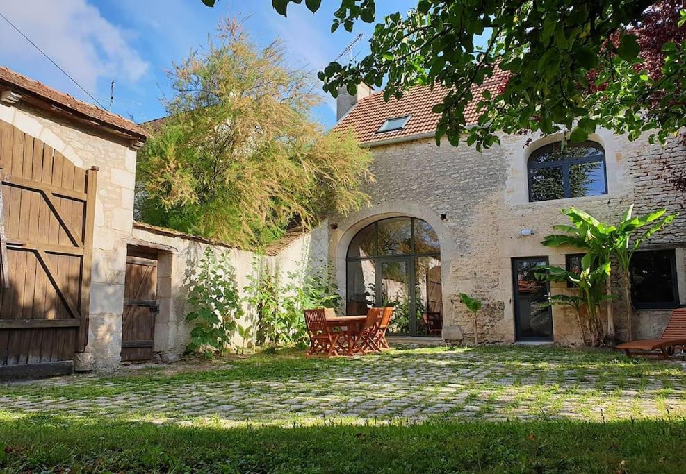 a house with a table and chairs in the yard at La maison d'art et d'hôtes in Leuglay