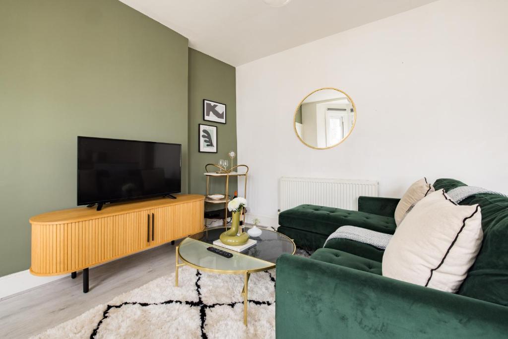 a living room with a green couch and a flat screen tv at The Brockwell Park Place - Bright 2BDR Flat in London
